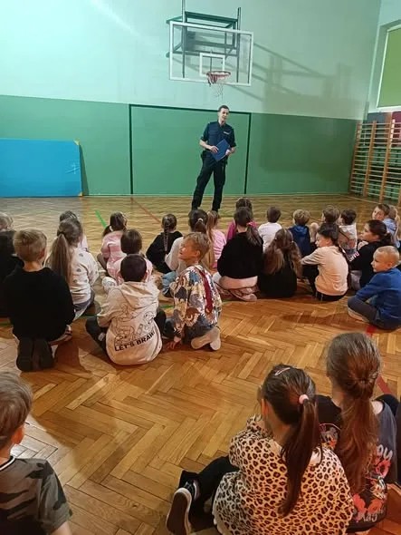 Dzielnicowy rozmawia z uczniami o bezpieczeństwie podczas wakacji